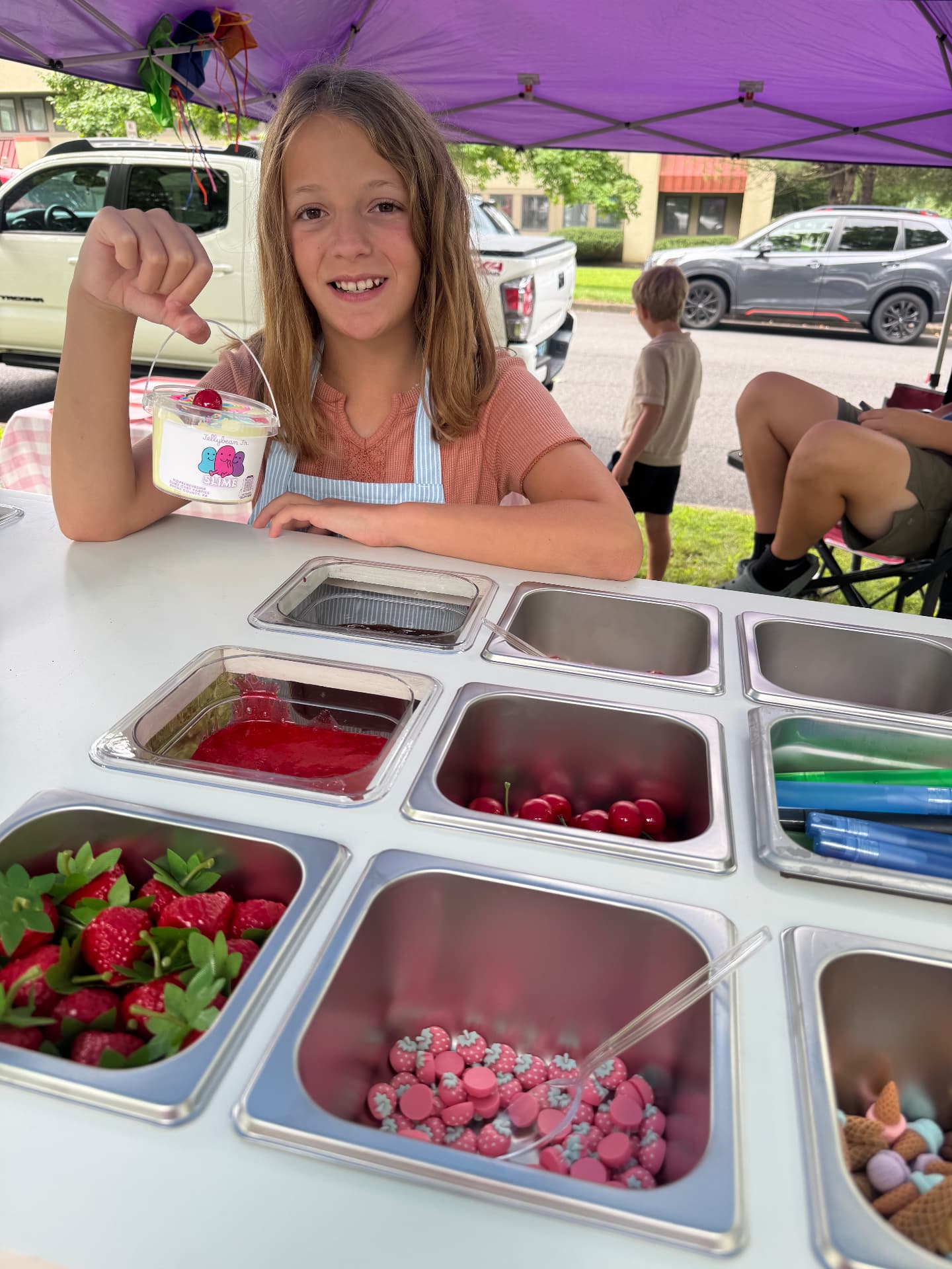 A young guest showing a bucket of Jellybean Jr. slime with sundae toppings